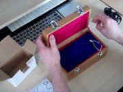 A person is opening a wooden box on a desk.